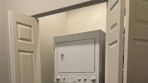 A compact laundry room with a washer and dryer, enclosed by white doors.