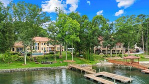 Une propriété au bord du lac, dotée d’un quai, d’une piscine et de plusieurs bâtiments de style architectural méditerranéen.