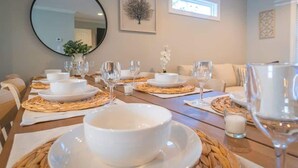 Comedor con una mesa dispuesta para cuatro, con platos, cuencos y vasos blancos.