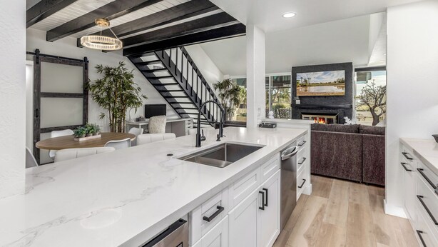 A modern kitchen with a marble countertop, a built-in stove, and a large window overlooking a garden.