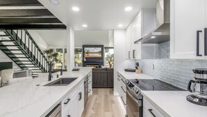 A modern kitchen with white cabinetry, a large island, and a view to the living area.