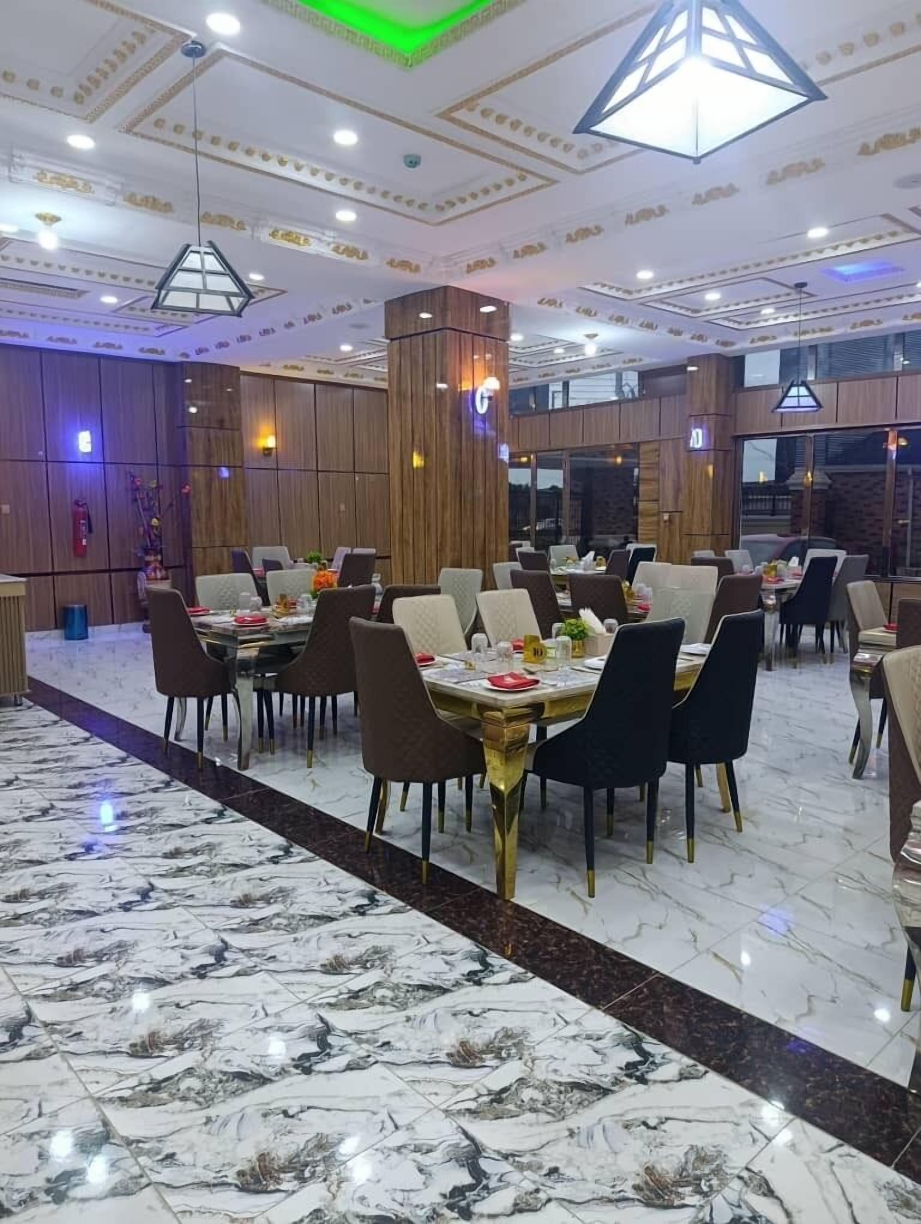 A spacious dining area with marble flooring and modern decor, featuring multiple tables and chairs.