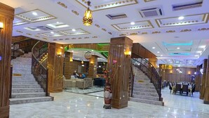 Eine großzügige Lobby mit Marmorböden, einer imposanten Treppe und modernen Leuchten.