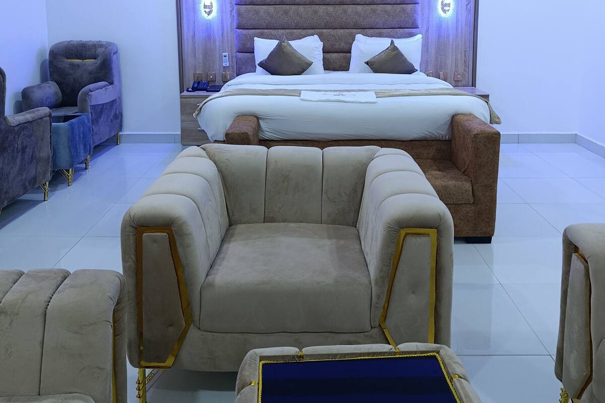 A modern bedroom with a large bed, two bedside lamps, and a plush sofa.