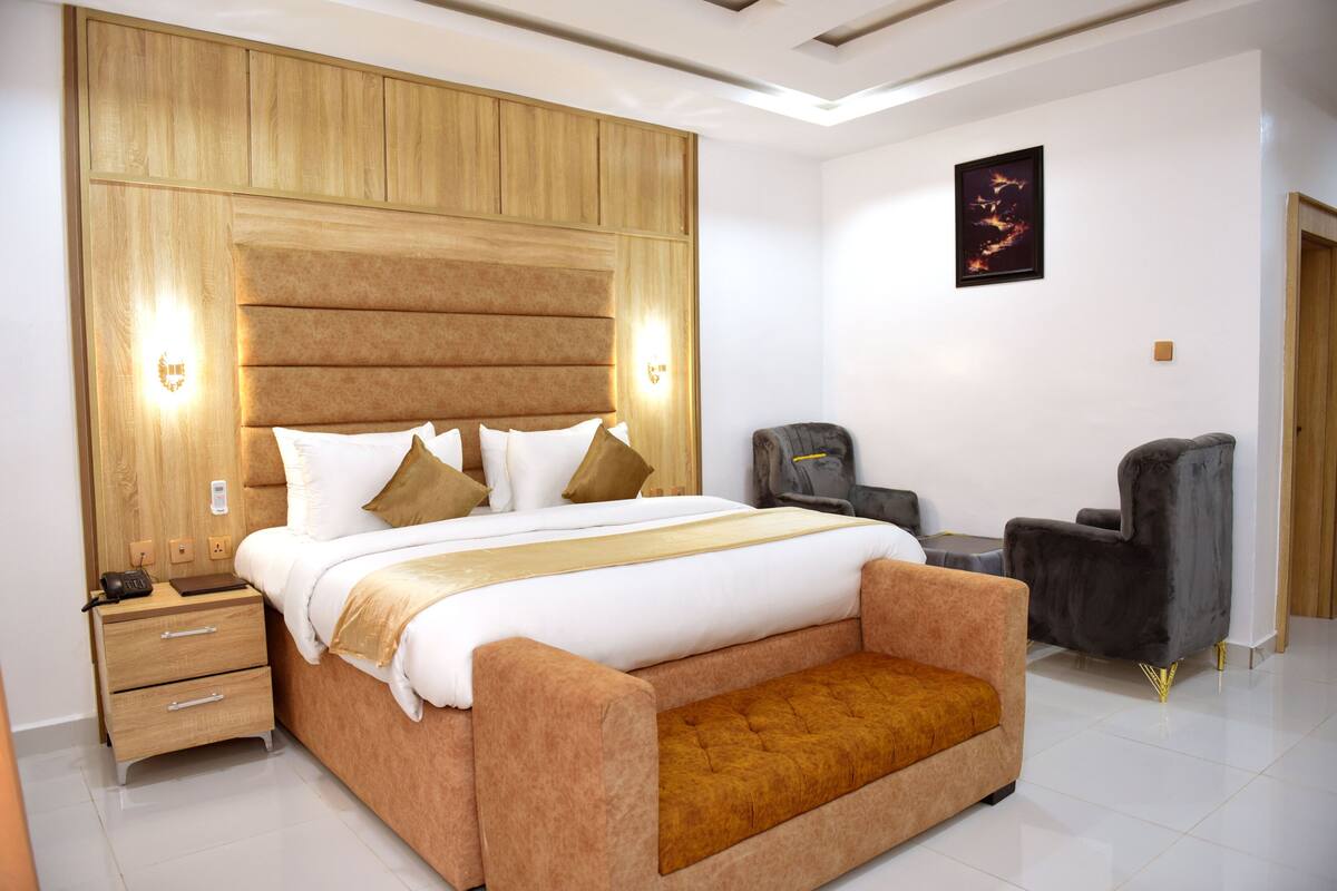 A modern bedroom with a large bed, bedside tables, a desk, and a chair.