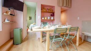 A compact living space with a dining area, kitchenette, and a TV mounted on the wall.