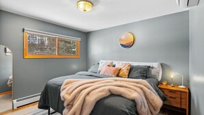 Een slaapkamer met een bed, nachtkastje en een nachttafeltje.