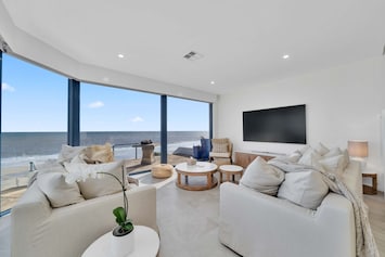 Ground-floor living room with stunning full ocean views, furnished with plush white sofas and a chic coffee table