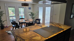 Une cuisine moderne dotée d’un grand îlot central, de chaises noires, d’une table à manger et de plantes en pot.