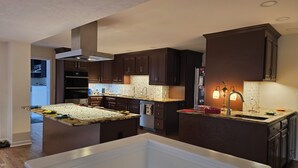 Une cuisine moderne avec des meubles en bois foncé, un îlot central et un four encastré.