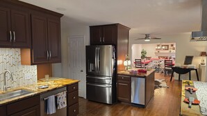 Une cuisine moderne avec des meubles en bois foncé, des appareils électroménagers en acier inoxydable et un plancher en bois.