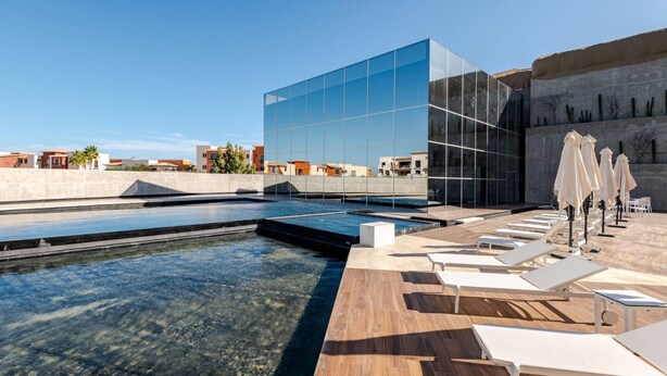 A rooftop pool area with clear water, lounge chairs, and umbrellas. - Brand new San Jose Condo (San José del Cabo)