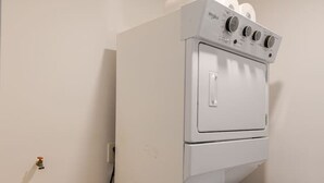 A compact laundry room with a stacked washer and dryer, a small sink, and a visible electrical outlet. - Brand new San Jose Condo (San José del Cabo)