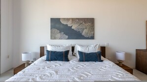 A bedroom with a large bed, two nightstands, and a wall-mounted painting. - Brand new San Jose Condo (San José del Cabo)