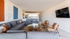 A modern living room with a sectional sofa, a glass coffee table, and leather armchairs. - Brand new San Jose Condo (San José del Cabo)