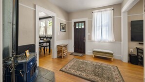 A living room with a fireplace, a bench, a television, and a door leading to another room. - Stay in the Elizabeth Page House, a modern bungalow, perfect for families. (Springfield)