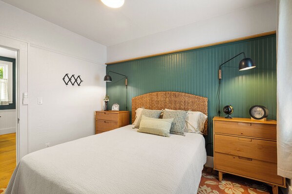 Un dormitorio con una cama, dos mesitas de noche, un aparador, un reloj de pared y un globo terráqueo.