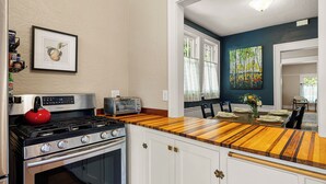 A kitchen with a gas stove, a red kettle, a Samsung toaster, and a wooden countertop. - Stay in the Elizabeth Page House, a modern bungalow, perfect for families. (Springfield)