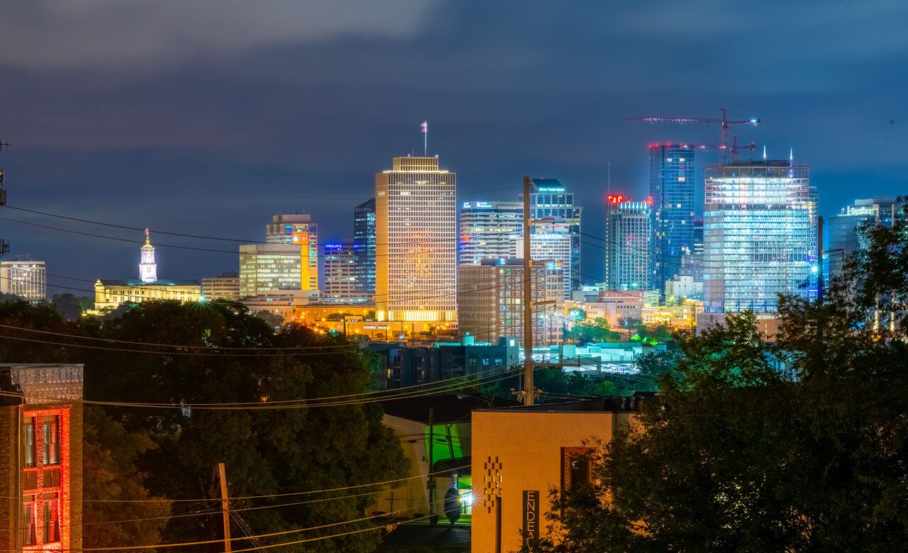 Un horizonte urbano nocturno con edificios iluminados y grúas de construcción.
