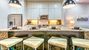 Una cocina moderna con una isla central, electrodomésticos de acero inoxidable y taburetes de bar.