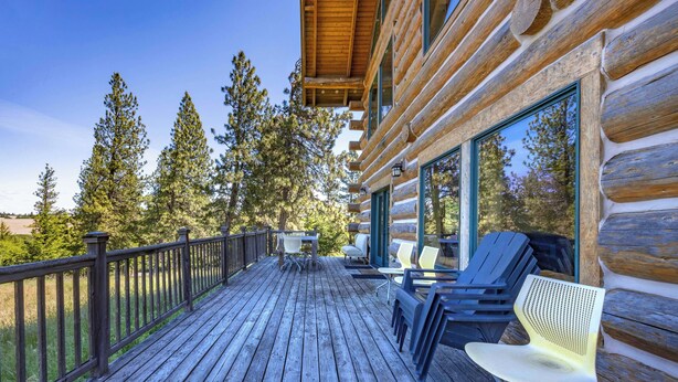 A wooden deck with outdoor seating and a view of trees.