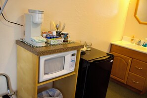 A kitchenette with a coffee maker, microwave, refrigerator, and a sink.