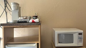 Una kitchenette con cafetera, microondas y refrigerador pequeño.