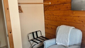 Una habitación con pared de madera, una silla de metal con una toalla y una puerta de madera.
