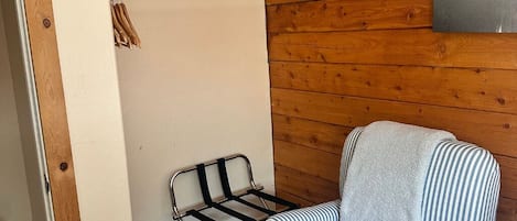 Une pièce avec un mur en bois, une chaise en métal sur laquelle est posée une serviette, et une porte en bois.
