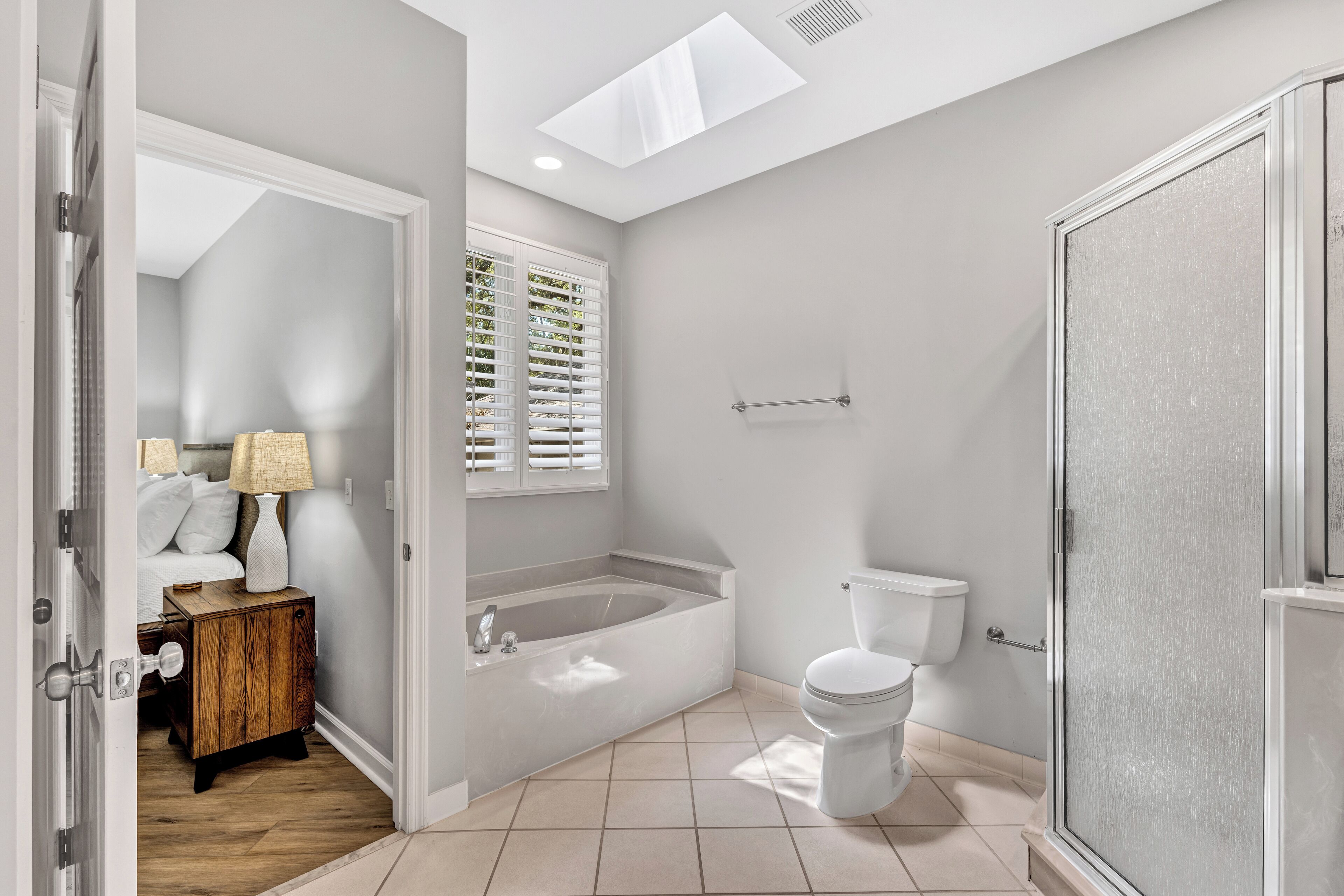 A modern bathroom with a bathtub, toilet, and shower.