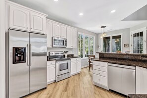 A modern kitchen with white cabinetry, stainless steel appliances, and a granite countertop.