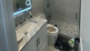 A modern bathroom with a glass shower enclosure, a marble sink, and a toilet. - BEAUTIFUL FULLY RENOVATED 3 BEDROOM APARTMENT (West New York)