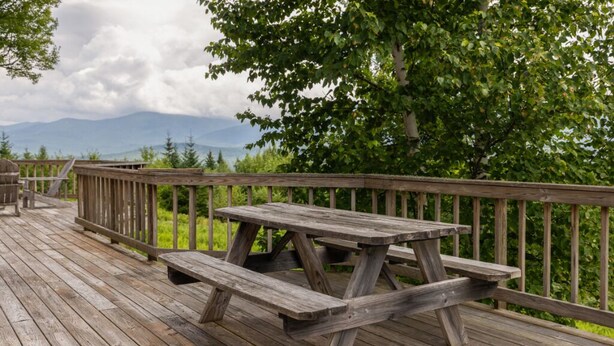 Une terrasse en bois avec une table de pique-nique et une rambarde.
