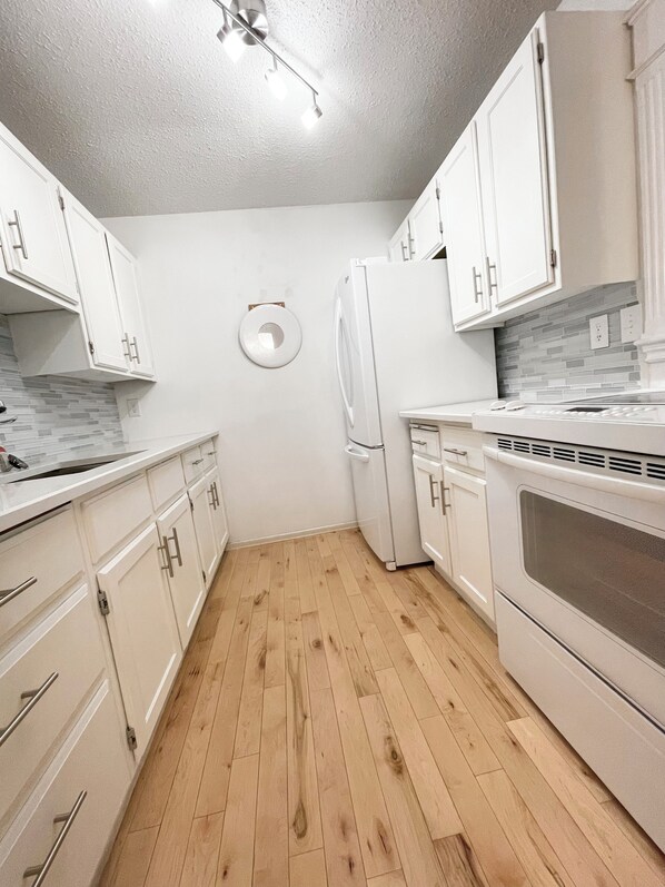 A modern kitchen with white cabinetry, a built-in oven, and a refrigerator. - Bright & Premium Charleswood Home (Winnipeg)