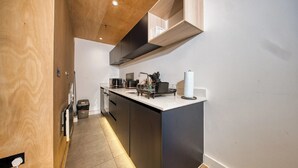 Una cocina moderna con una isla central, electrodomésticos integrados y techo de madera.