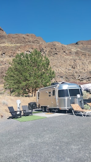 A recreational vehicle parked in a parking lot with a mountainous backdrop.
