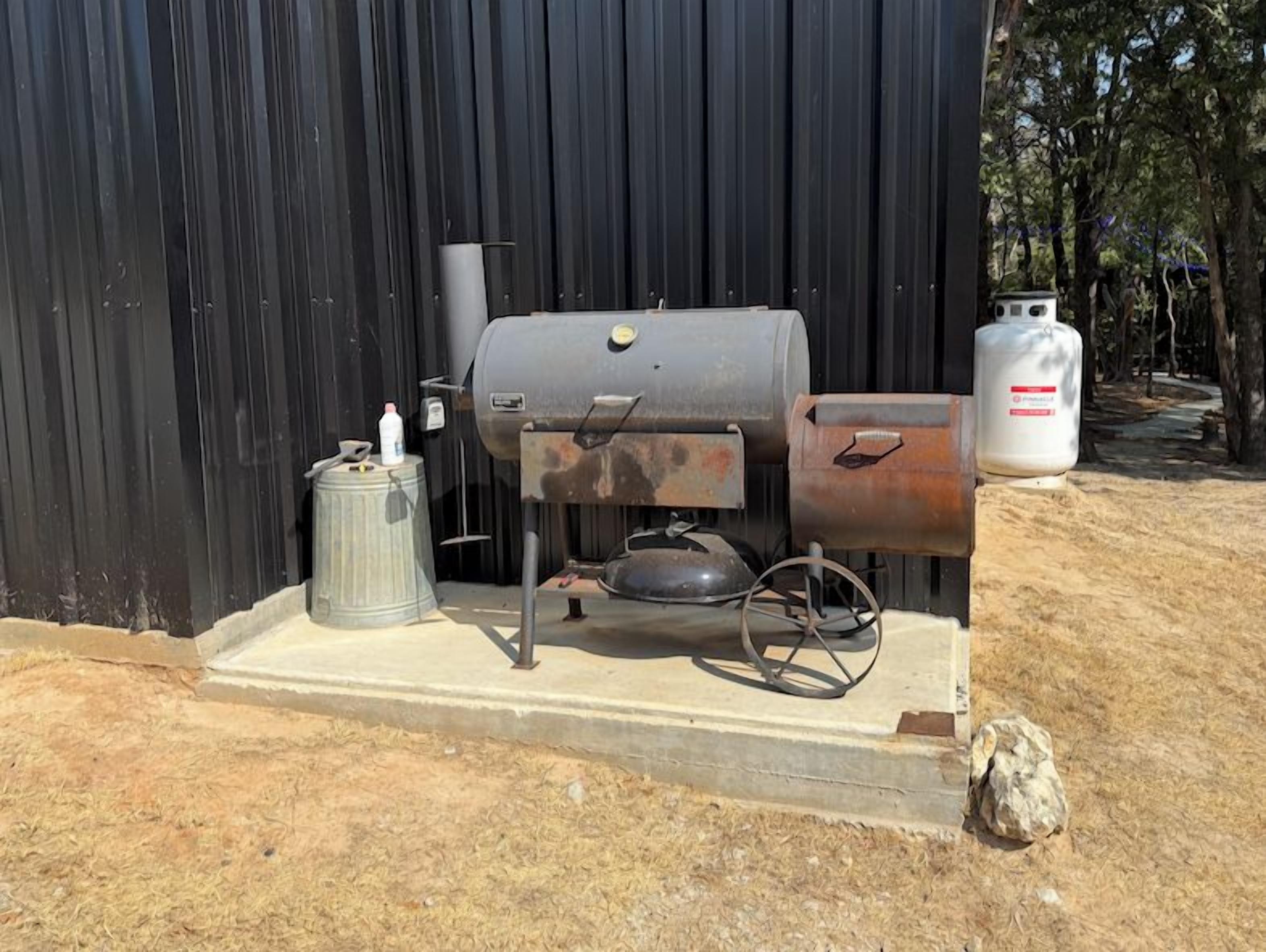 Una parrilla de gas portátil con tanque de metal, cilindro de propano y cuerpo de metal.