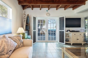 Una sala de estar acogedora con un sofá, una mesa de centro, un televisor y una puerta que da a un espacio exterior.