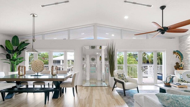 A spacious living area with a dining table, seating, a ceiling fan, and a view of the outdoors.