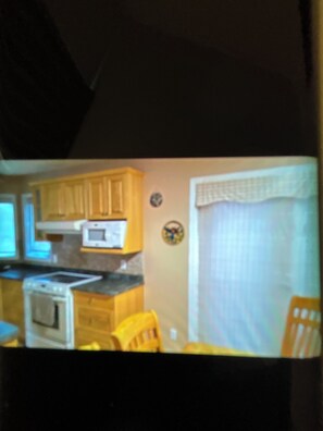 A kitchen with wooden cabinets, a microwave, and a stove. - Enjoy a rural 2 bedroom 2 bath family home with garage in north west Manitoba. (Mafeking)