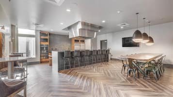 Een moderne keuken met een centraal eiland, barkrukken en een eettafel met stoelen.