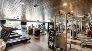 Un gimnasio con cintas de correr, elípticas y equipo de levantamiento de pesas.