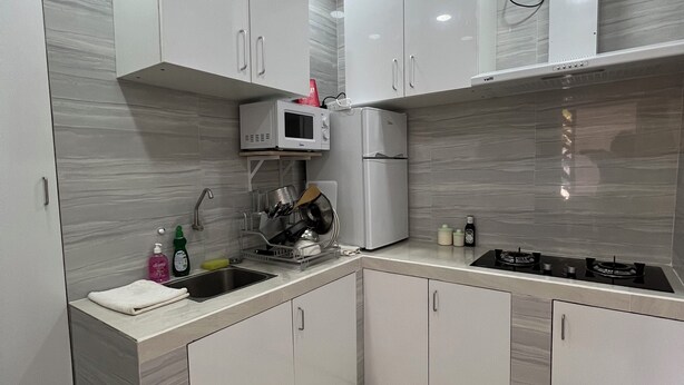 A modern kitchen with white cabinets, a built-in microwave, a refrigerator, and a gas stove.