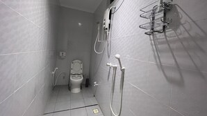 A small, tiled bathroom with a toilet, a shower, and a hand dryer.