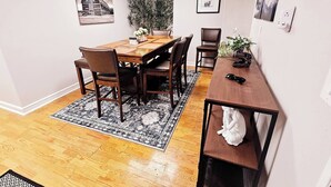 A dining area with a wooden table, chairs, a rug, and artwork on the walls.