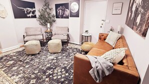 A cozy living room with a brown leather sofa, two armchairs, and a patterned rug.
