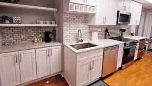 A modern kitchen with white cabinetry, a brick backsplash, and a stainless steel refrigerator.