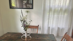 Una mesa de comedor con un jarrón de flores, sillas de madera y un cuadro en la pared.