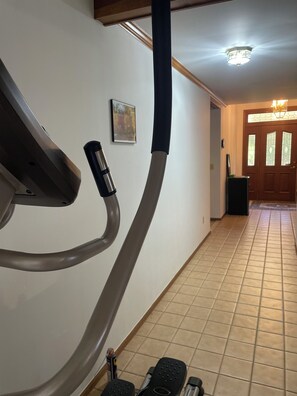 Un gimnasio en casa con una bicicleta estática, una cinta de correr y una botella de agua en el suelo.