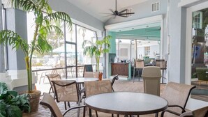 An indoor seating area with round tables and chairs, large windows, and potted plants. - Amazing 3BDR House w/ pool (Kissimmee)